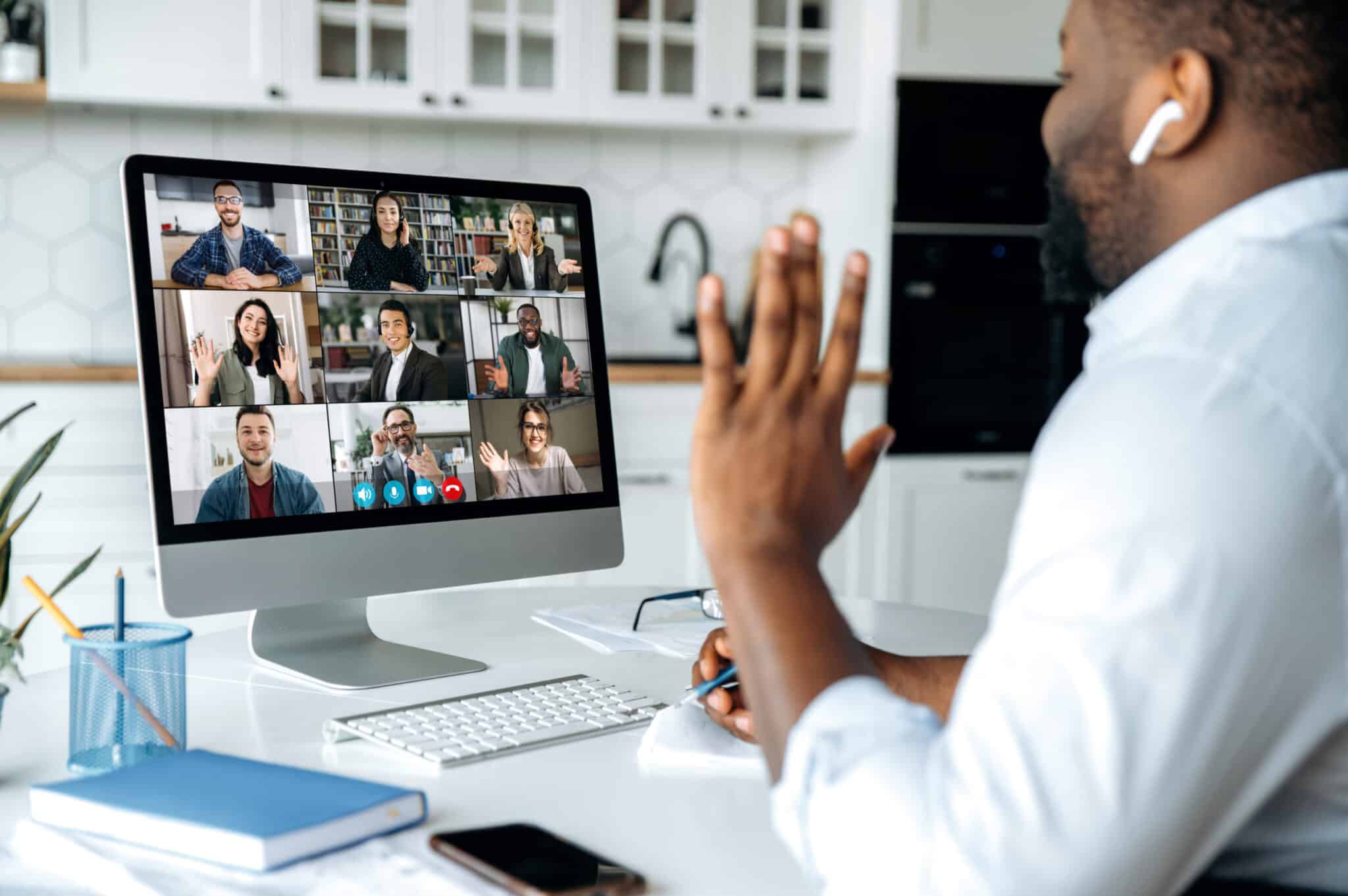 Video call, online conference. Over shoulder view of african american man at computer screen with multinational group of successful business people, virtual business meeting, work from home concept Video call, online conference. Over shoulder view of african american man at computer screen with multinational group of successful business people, virtual business meeting, work from home concept