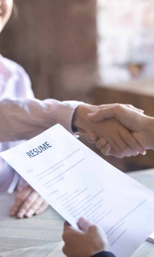 Smiling young woman and man handshake. Businesspeople shaking hands. Human resources, successfully passing the interview, hr concept. Close up resume paper